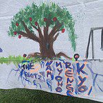 A mural of an apple tree with graffiti on it.